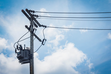 Electric tranformer on the eletric Cement-pole. White clouds and blue sky