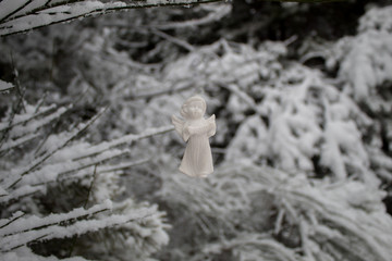White angel figurine on a background of a winter snowy landscape. Christmas landscape with an angel and a forest in the snow.