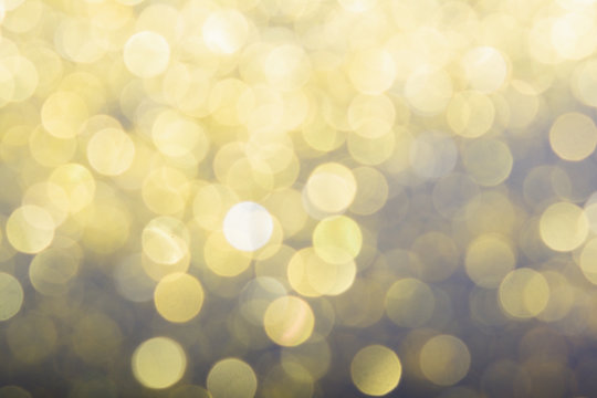 Abstract blurred glitter bokeh background in gold, on black