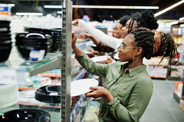 Group of african womans look color plates on supermarket shelves.