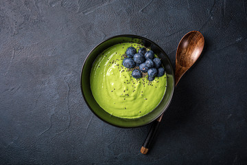 Breakfast detox green smoothie bowl from banana and spinach on black background. Healthy food...