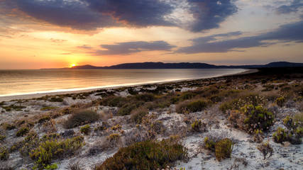 Obraz premium Troia, Portugal - September 13, 2019: Sunset over the Troia peninsular from Praia da Malha da Costa with a view towards Cabo Espichel and the Arrabida mountains, Portugal