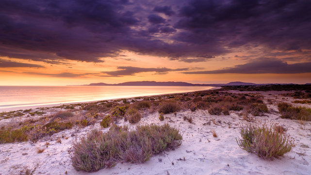 Troia, Portugal - September 13, 2019:  Sunset over the Troia peninsular from Praia da Malha da Costa with a view towards Cabo Espichel and the Arrabida mountains, Portugal