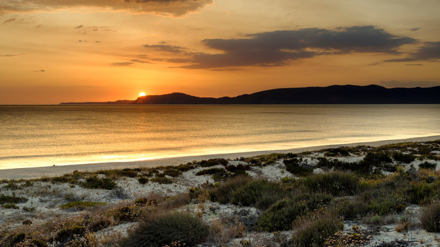 Troia, Portugal - September 13, 2019:  Sunset over the Troia peninsular from Praia da Malha da Costa with a view towards Cabo Espichel and the Arrabida mountains, Portugal