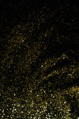 Golden glitter scattered on the black card background, top view. Abstract pattern created by hand, imitaion of storm, selective focus