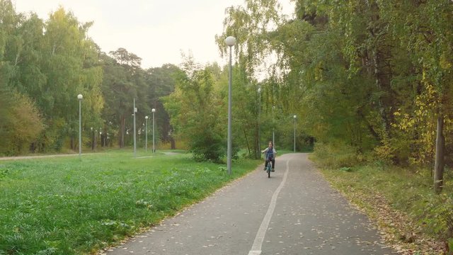 Boy riding bicycle in park. Adorable excited teenage boy cycling bike and expressing emotions in beautiful autumn park.