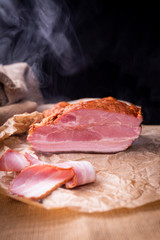 Bacon, freshly smoked, cut in slices on a wooden board. Cold cuts prepared in a traditional way.