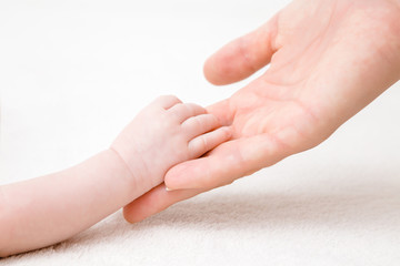 Young mother hand holding her infant little hand. First touch. Lovely, emotional, sentimental...