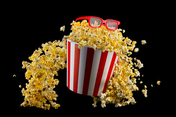 Flying popcorn from striped bucket isolated on black background