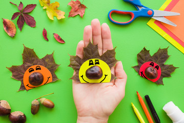 Girl hand holding cute hedgehog who created from brown maple leaf, chestnut and paper. Autumn...