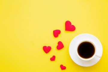White cup of black coffee with red hearts on bright yellow table. Empty place for nice, lovely, inspirational text, quote or saying.