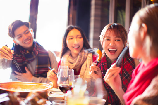 Happy Young Friends Eating Hot Pot In Restaurant At Winter