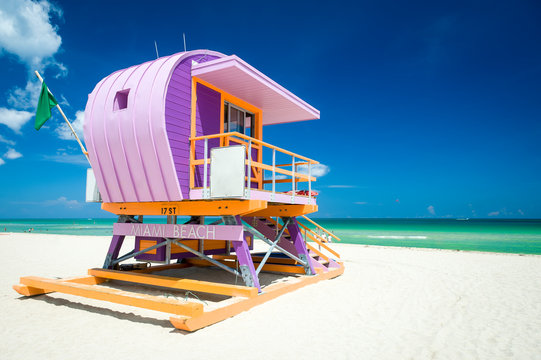 Vibrant sunny view of lifeguard tower painted pastel colors under bright blue sky on South Beach, Miami, Florida