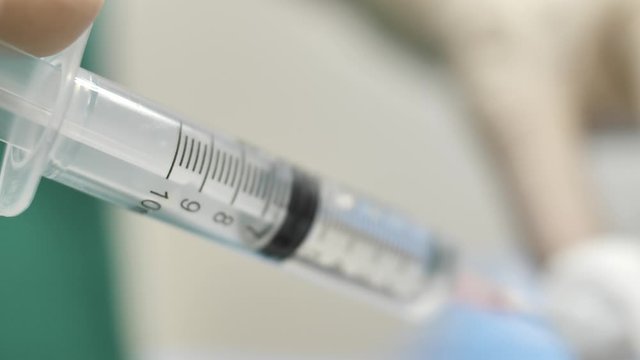 Close up on syringe filled by doctor in healthcare clinic