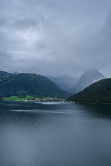 Mountains are covered with clouds over a lake in the Austrian Alps on a cloudy day. Lake Achensee Austria.