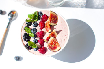 Smoothie bowl morning breakfast on the white bright sunny background. Top view
