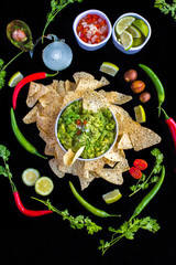 Guacamole with all the ingredients, authentic mexican recipe on a black background. Includes pico de gallo (tomato, onion and coriander). Top view for instagram