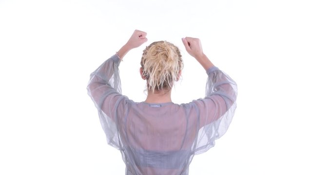 Rear view of happy blonde woman with fists raised