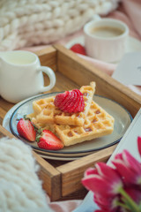 Waffles with strawberries on wood board with tulips