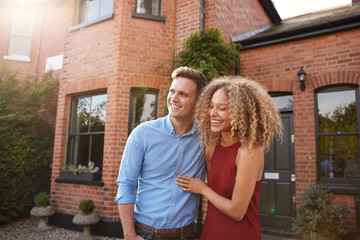 Excited Young Couple Standing Outside New Home Together