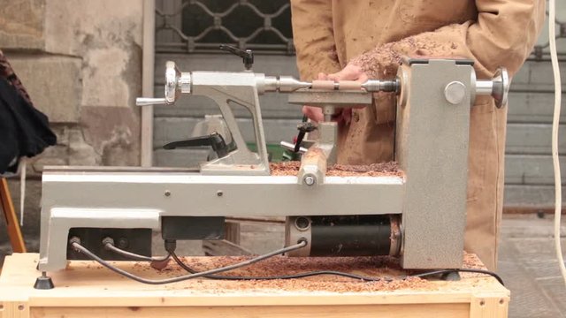 Carpenter man working wood. Manual worker using lathe to smooth a small piece of hardwood