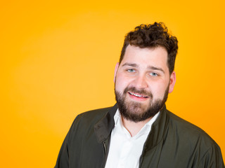 one cool man with black beard and black hair is posing in front of orange background