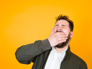 one cool man with black beard and black hair is posing in front of orange background