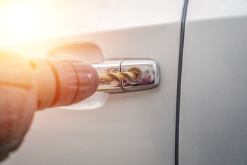 Car thief. Close - up of a man's hand opening the car with a screwdriver. Photo with illumination,...