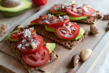 Bruschetta with avocado and tomatoes. Food for a healthy lifestyle. Whole-grain cereal bread with vegetables and Brazil nuts. Healthy vegan breakfast