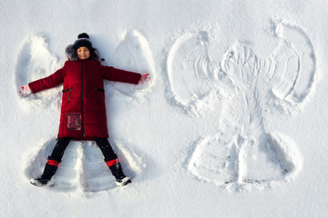 The girl lies in the snow and makes a snow angel - Powered by Adobe