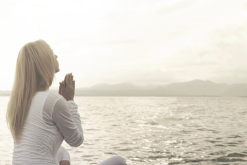 woman prays meditating in front of a ocena view