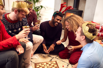 Group Of Friends Playing Board Games After Enjoying Christmas Dinner At Home