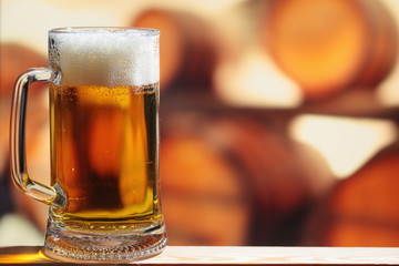Mug of light beer against wooden beer  barrel
