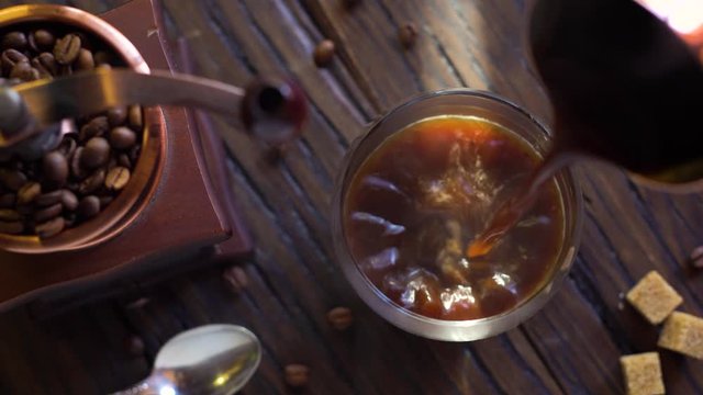 Freshly brewed coffee from cezve is poured into a coffee cup. Steam comes out of the cup, an old coffee grinder is in the composition. 4K video.