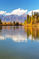 Obraz premium Beautiful autumn landscape with reflection in the water of mountains and yellowed trees on a sunny day. Siberia, Baikal region, Buryatia, Irkut river, Tunka valley