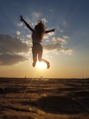 silhouette of young woman jumping on the beach