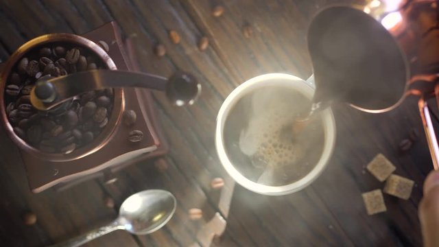 Freshly brewed coffee from cezve is poured into a coffee cup. Steam comes out of the cup, an old coffee grinder is in the composition. 4K video.