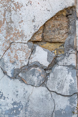 Texture of messy old cracked stone or cement wall in the sunlight for pattern, background. Cracked concrete wall as background. Selective focus old cracked stucco