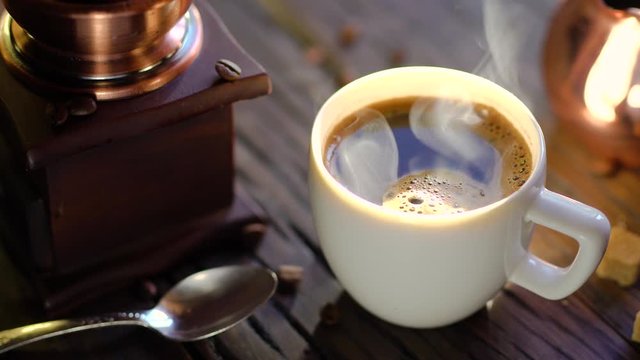 Coffee cup with freshly brewed coffee on an old vintage table. Steam rises from the cup.