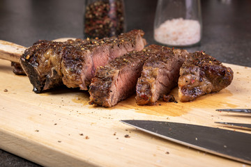 Chef hands slicing beef steak with knife on wood cutting desk.