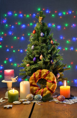 Christmas tree with a ritual round bread, the candles, gingerbread biscuits and ornate eggs on the table