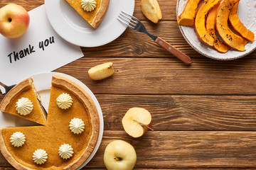 top view of tasty pumpkin pie, apples and thank you card on wooden rustic table