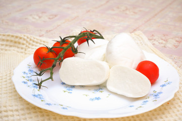 Mozzarella di buffalo with sweet chery tomatoes on the white clean plate