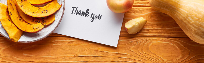 top view of pumpkin, ripe apples and thank you card on wooden table, panoramic shot