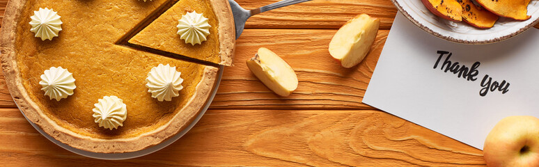 top view of pumpkin pie with thank you card on wooden table with apples, panoramic shot