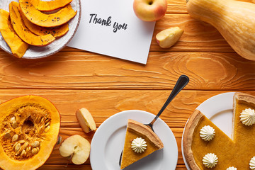 top view of pumpkin pie, ripe apples and thank you card on wooden table