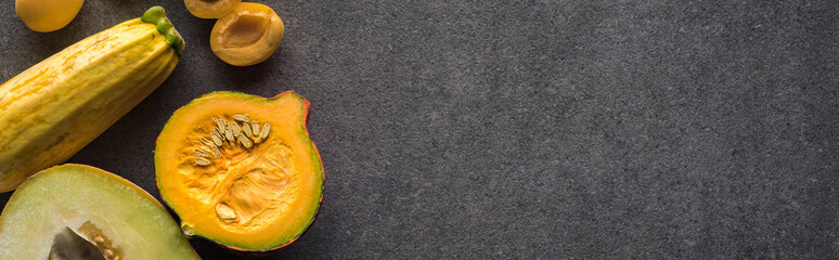 top view of yellow fruits and vegetables on grey textured background with copy space, panoramic shot