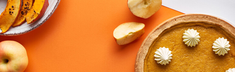top view of pumpkin pie, ripe apples on orange background, panoramic shot