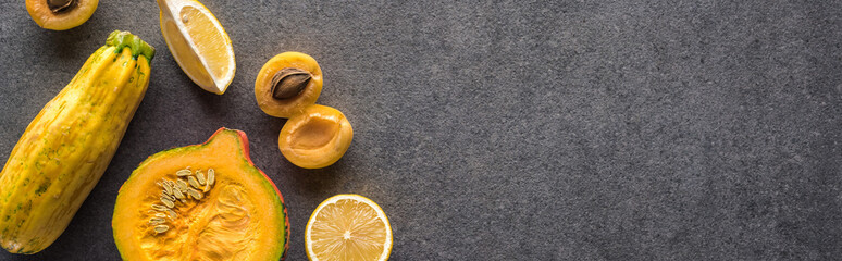 top view of yellow fruits and vegetables on grey textured background with copy space, panoramic shot