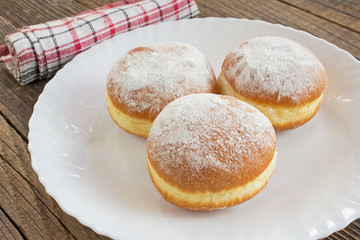 Berliner donuts in plate on wooden table